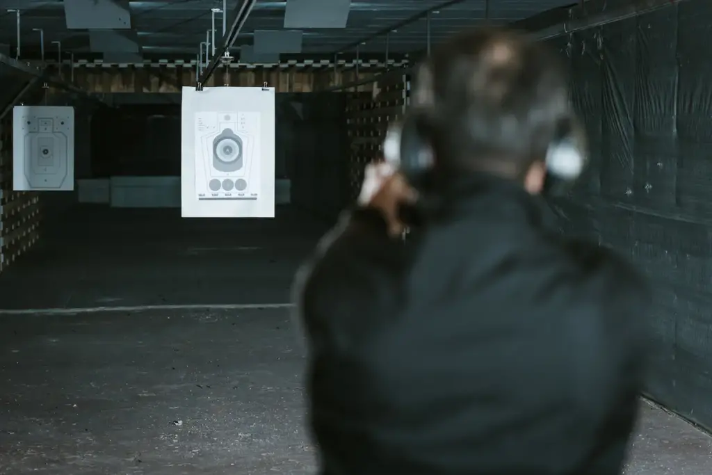 View Of Man Aiming Gun At Target In Shooting Range